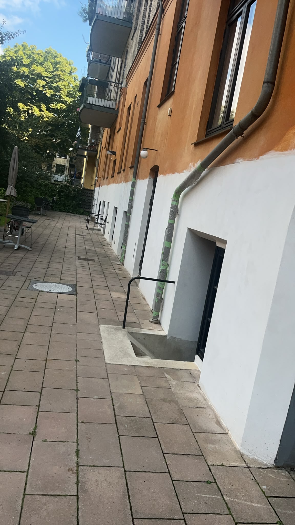 Kalkning af facade med afdækkede nedløbsrør og kældernedgang
